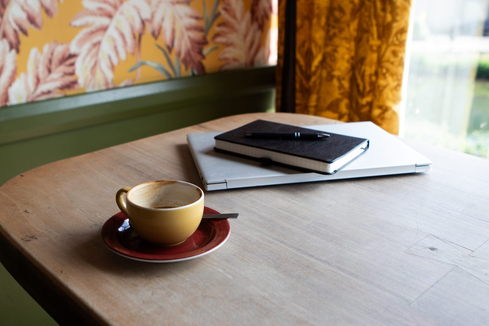 A coaching desk with a notebook, laptop and coffee, set up for an online session