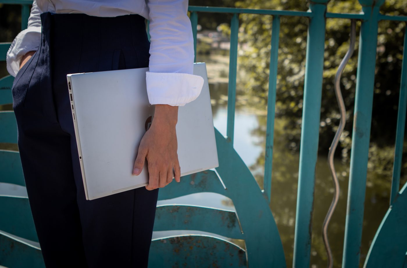 A laptop held under one arm outdoors, ready for a session anywhere